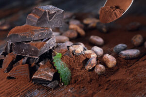 Dark chocolate pieces, cocoa powder and cocoa beans on a wooden table